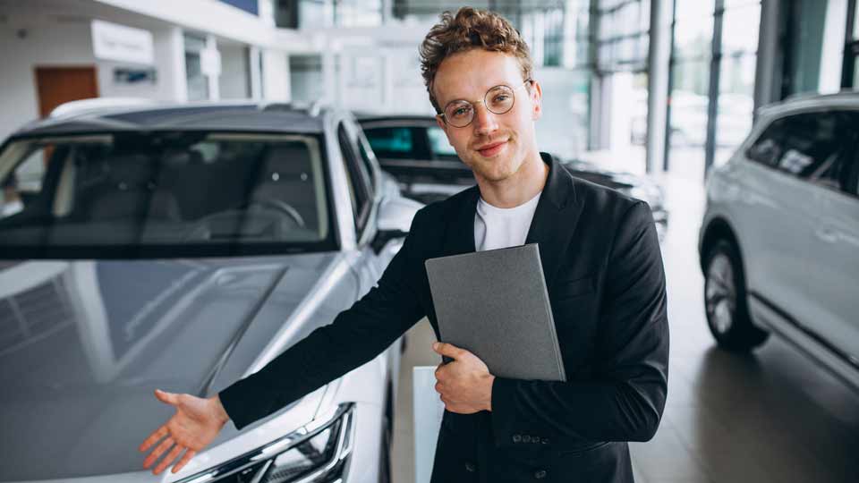 Ein Verkäufer zeigt auf ein Auto und erklärt dem Kunden die Konditionen beim Auto verkaufen Deggendorf